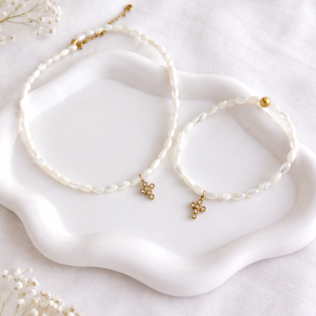 Collier femme en perles de nacre blanches avec pendentif croix dorée en acier inoxydable porté autour du cou