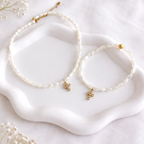 Collier femme en perles de nacre blanches avec pendentif croix dorée en acier inoxydable porté autour du cou